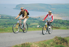 Two cyclists riding with Newport beach in the distance